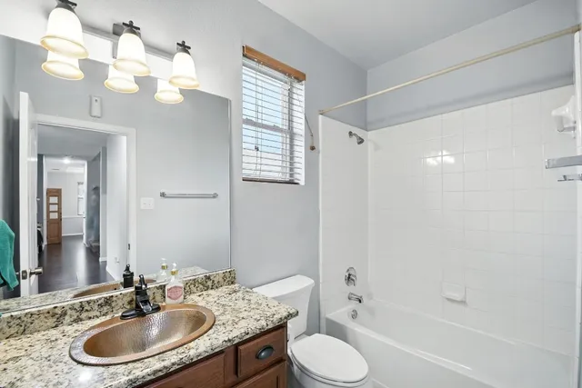 a bathroom with a granite countertop sink a toilet a mirror a bathtub and shower