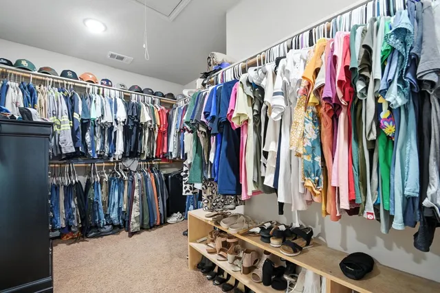 a view of walk in closet with clothes and shoes