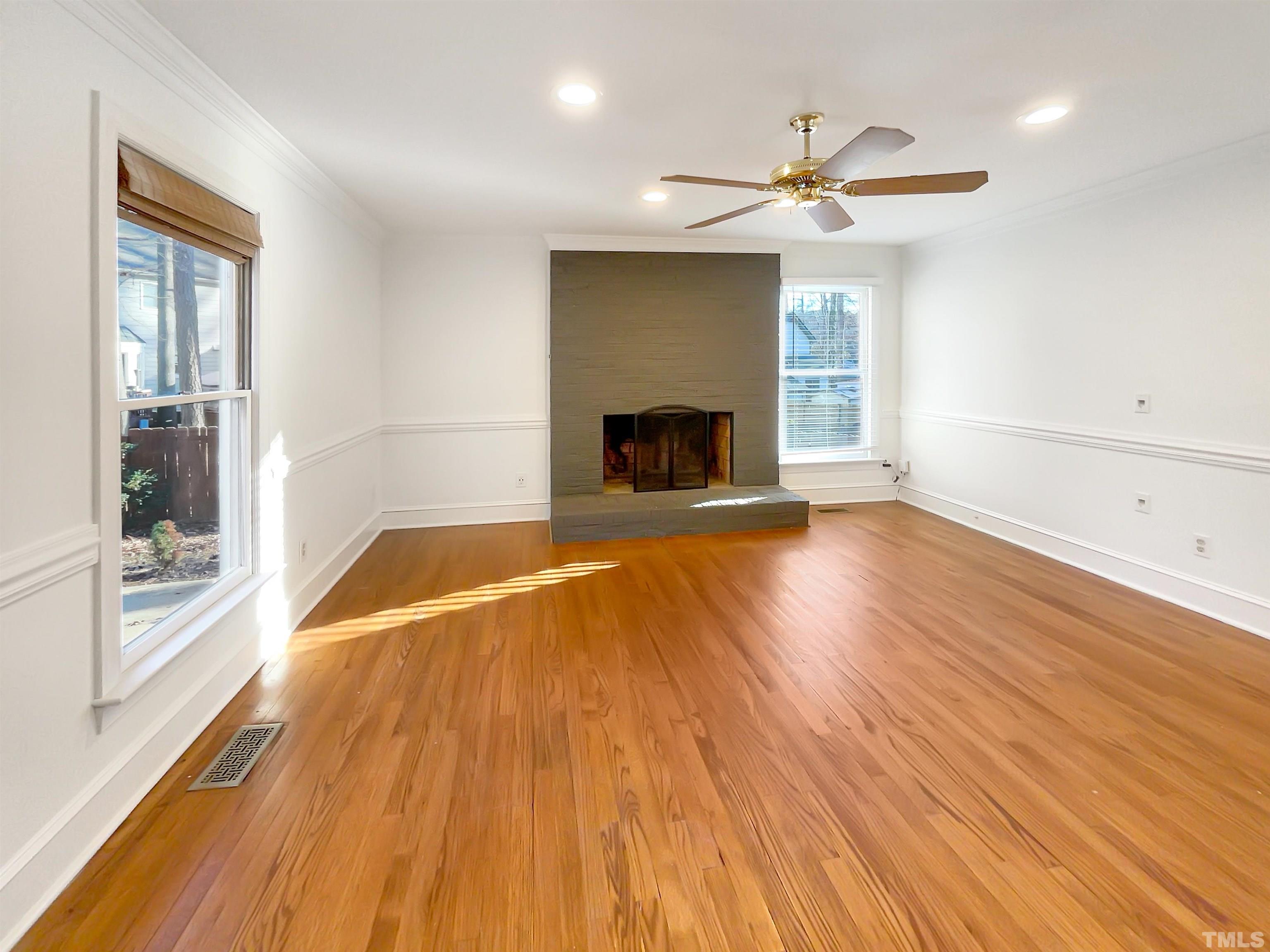 500 Chapwith Road Garner, NC 27529 - Photo 3 of 17 an empty room with wooden floor a fireplace and windows