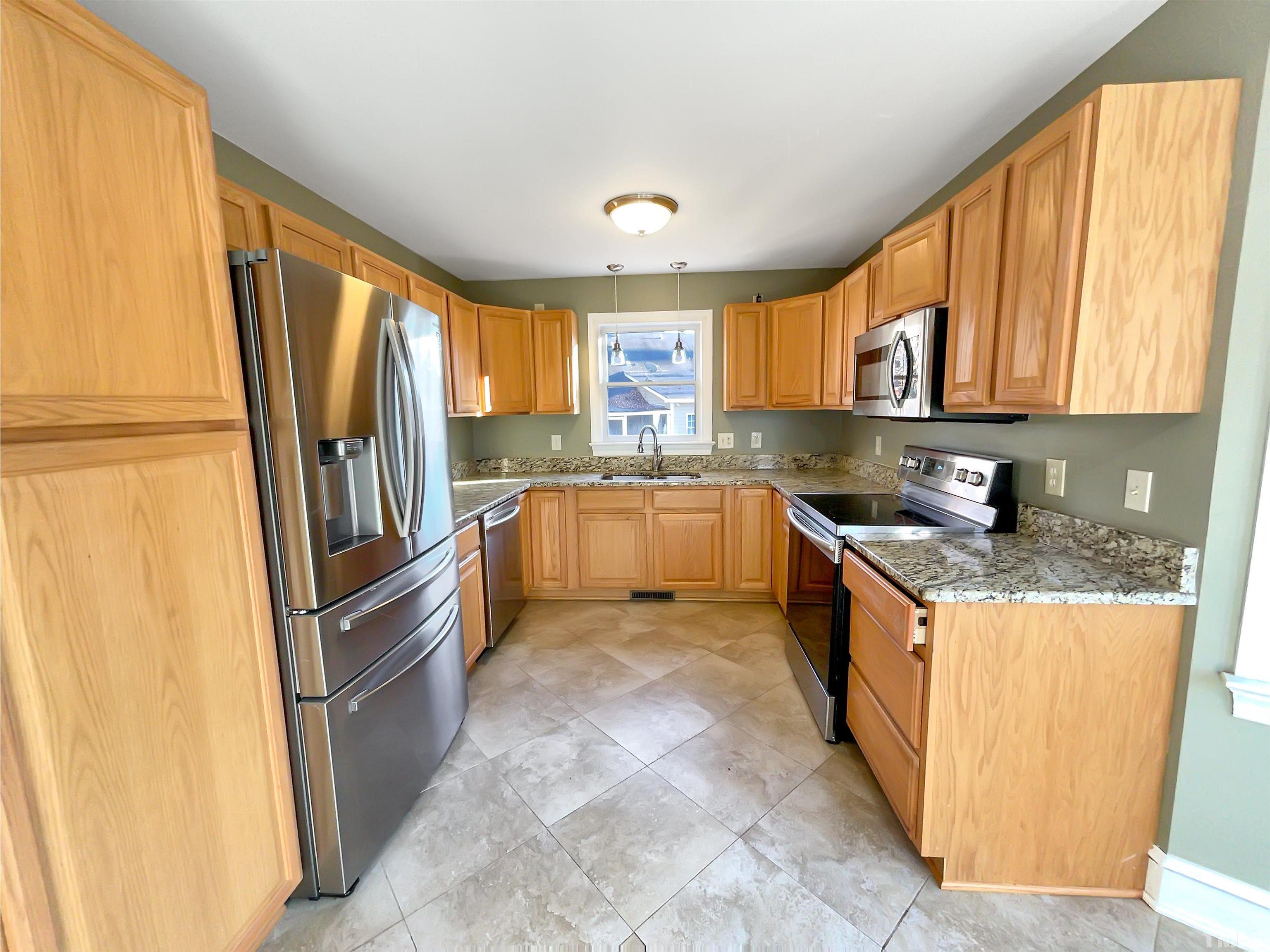 500 Chapwith Road Garner, NC 27529 - Photo 4 of 17 a large kitchen with stainless steel appliances granite countertop a refrigerator a sink dishwasher a stove a dining table and chairs with wooden floor