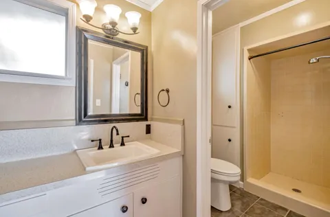 a bathroom with a granite countertop sink mirror vanity and toilet