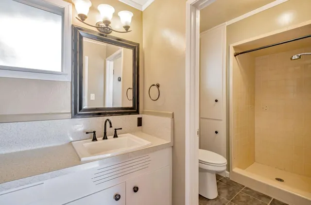 a bathroom with a granite countertop sink mirror vanity and toilet