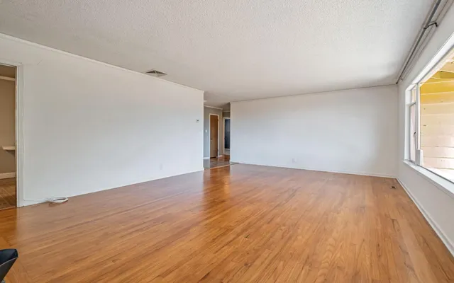 an empty room with wooden floor and windows