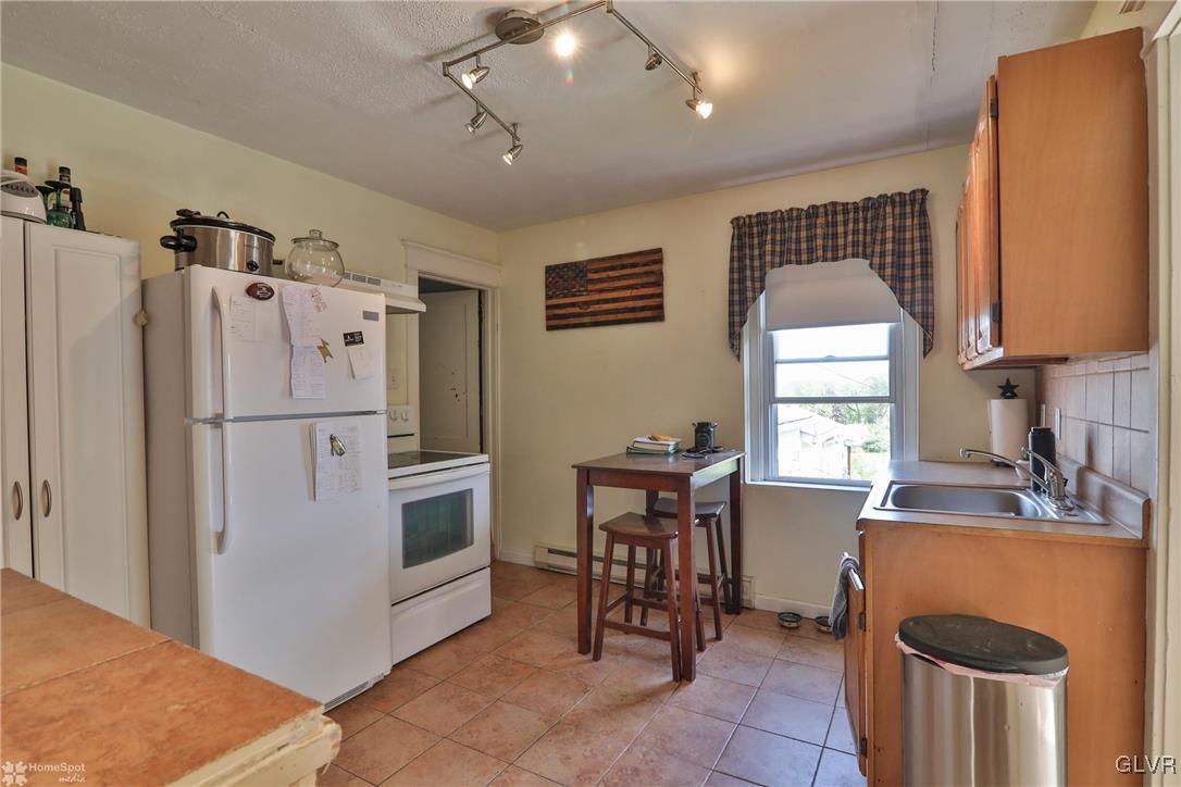 5562 Main Street Whitehall, PA 18052 - Photo 13 of 50 a kitchen with granite countertop a refrigerator a sink a stove and a dining table