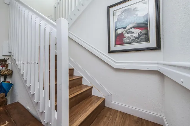 a view of staircase with wooden floor and fan