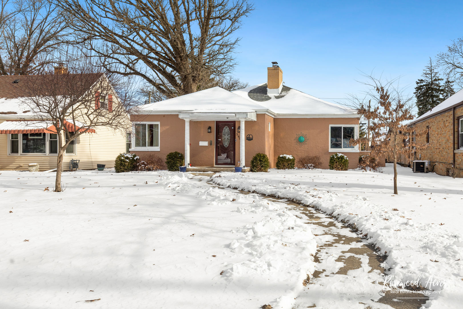 a front view of a house with a yard covered in snow