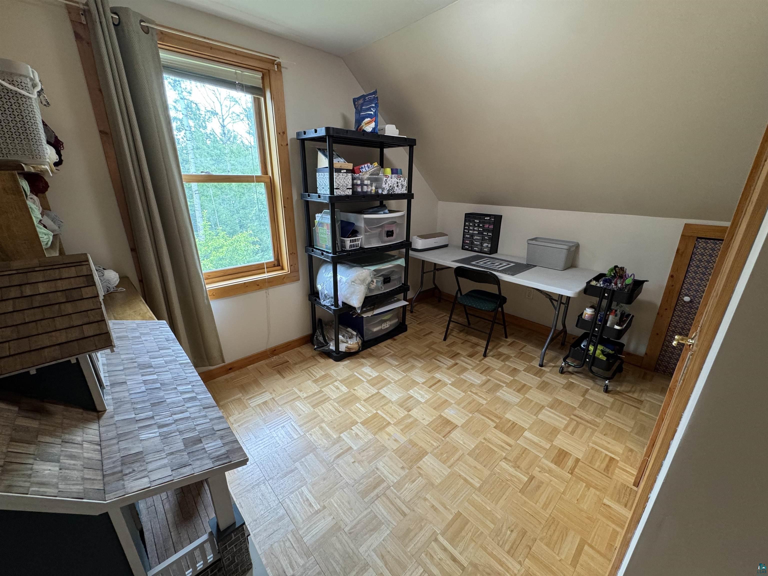 1745 Becks Road Maple, WI 54854 - Photo 22 of 46 Sloped ceiling room featuring wood-finish flooring, a wood-framed window with trim, and a paneled door with wood trim