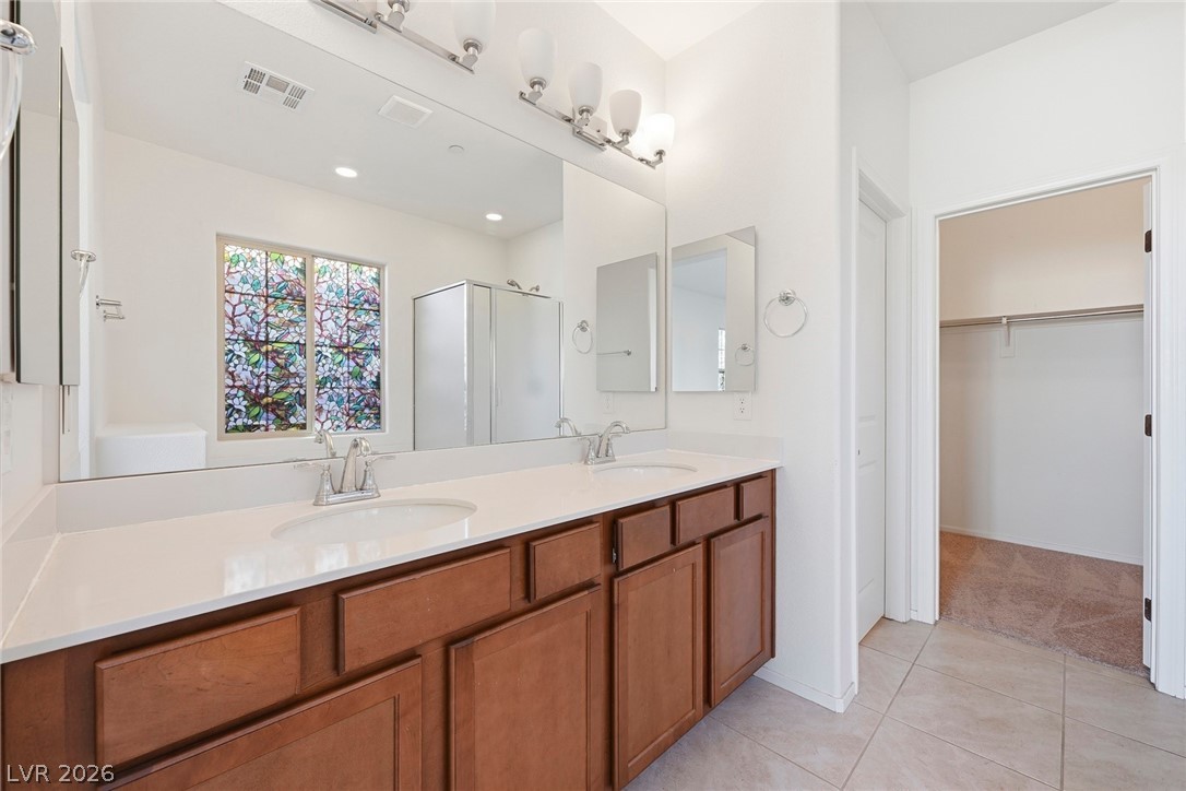 250 Dedication Avenue Henderson, NV 89011 - Photo 23 of 67 Full bath featuring a stall shower, double vanity, a spacious closet, and light tile patterned floors