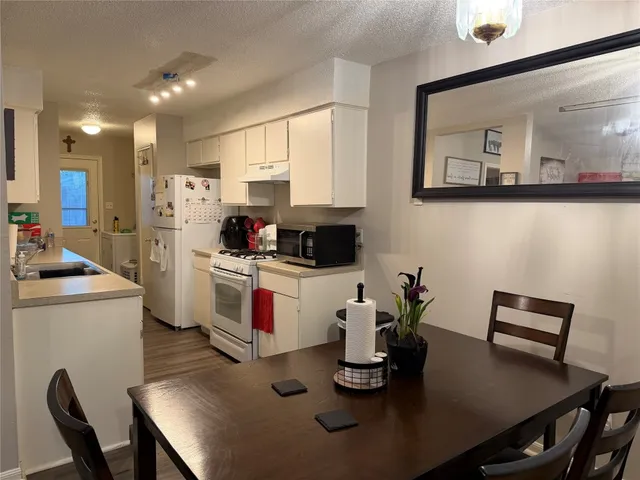 a kitchen with a table chairs white stove and cabinets