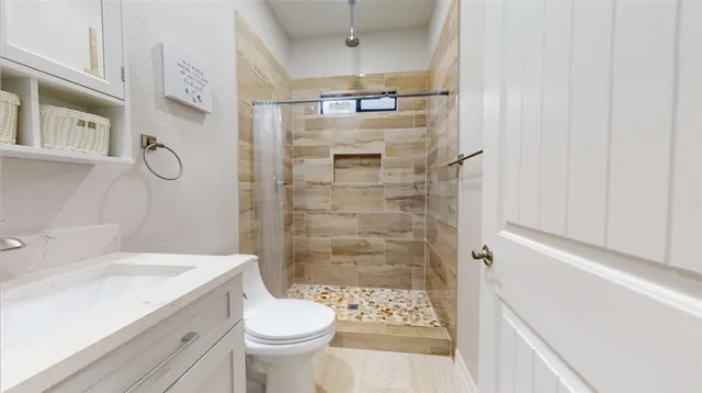 a bathroom with a granite countertop sink a toilet and shower