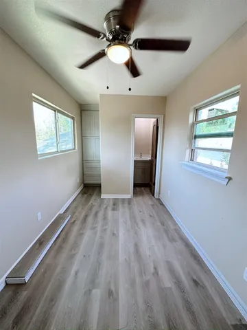 a view of empty room with wooden floor and fan