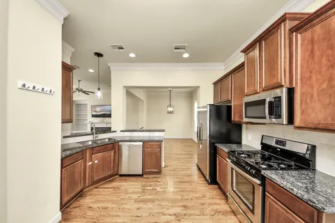 a large kitchen with stainless steel appliances granite countertop a stove top oven a sink and dishwasher