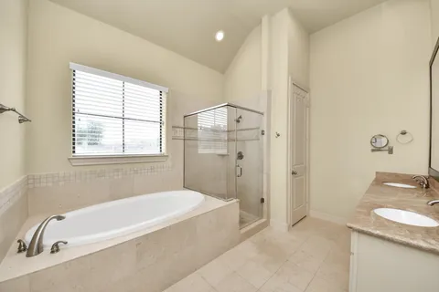 a bathroom with a granite countertop tub sink and mirror