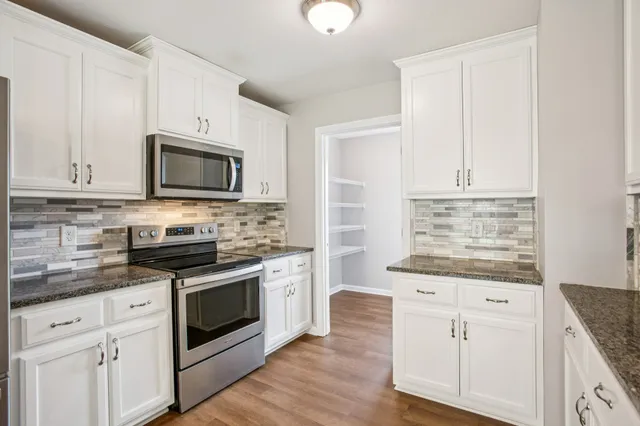 a kitchen with granite countertop white cabinets and appliances