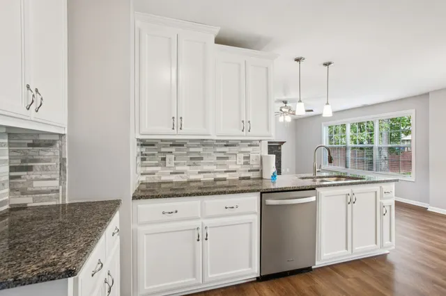 a kitchen with granite countertop white cabinets and white appliances