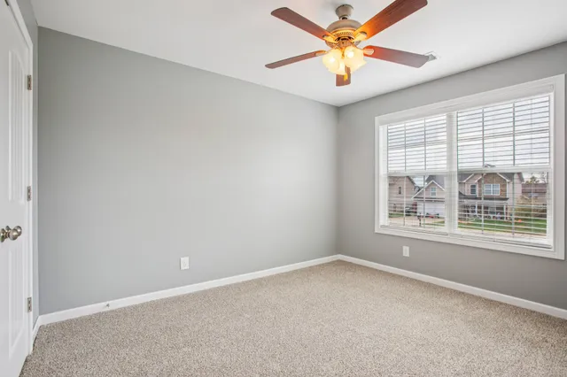 an empty room with a window and a fan
