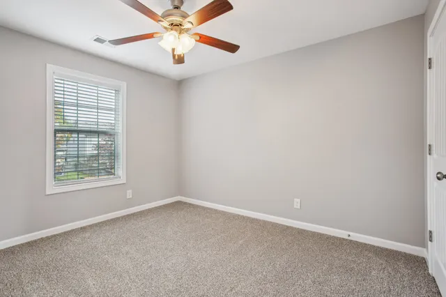 an empty room with a window and a fan
