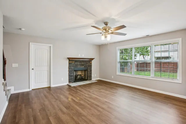 a view of an empty room with a window and wooden floor