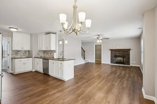 a large kitchen with granite countertop a stove a sink dishwasher a microwave oven a stove and white cabinets with wooden floor