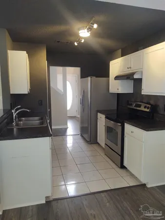 a kitchen with stainless steel appliances a refrigerator a sink and white cabinets
