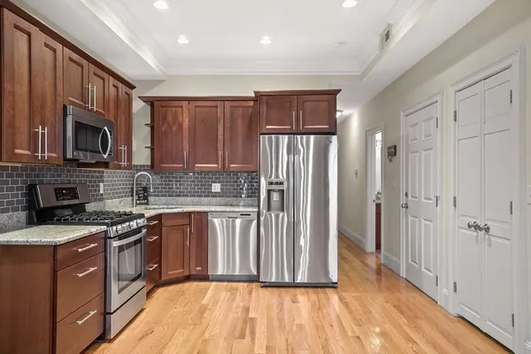 a kitchen with stainless steel appliances granite countertop a stove a sink dishwasher a refrigerator and a microwave oven with wooden floor