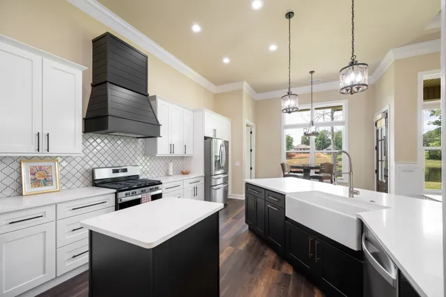 a large kitchen with stainless steel appliances kitchen island granite countertop a refrigerator a stove a sink dishwasher and white cabinets with wooden floor