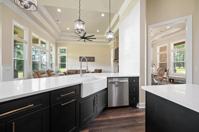 a kitchen with kitchen island a sink a stove a refrigerator and white cabinets with wooden floor