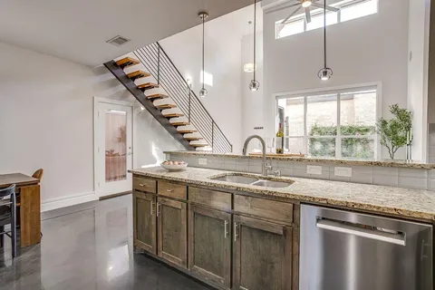 a kitchen with stainless steel appliances granite countertop a sink a stove and a wooden floor
