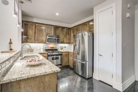 a kitchen with granite countertop stainless steel appliances a refrigerator stove top oven and sink