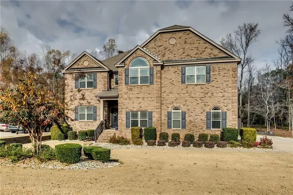 a view of a brick house with large windows and large trees