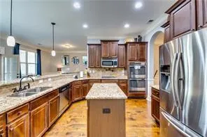 a large kitchen with kitchen island a stove a sink dishwasher and wooden cabinets