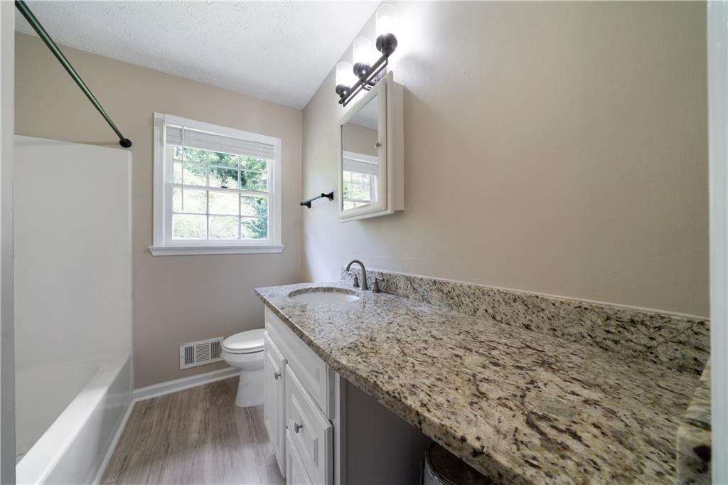 256 Powder Springs Street, Unit A Hiram, GA 30141 - Photo 13 of 16 a bathroom with a granite countertop sink a toilet and a mirror