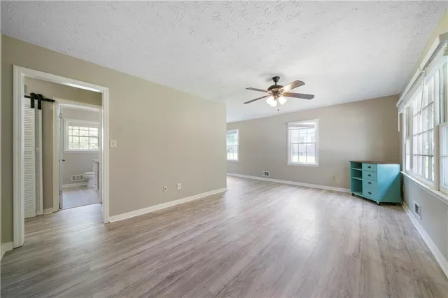 a view of an empty room with a window and wooden floor