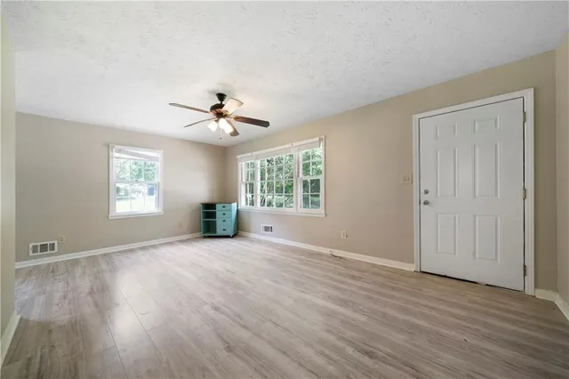 a view of an empty room with a window and wooden floor