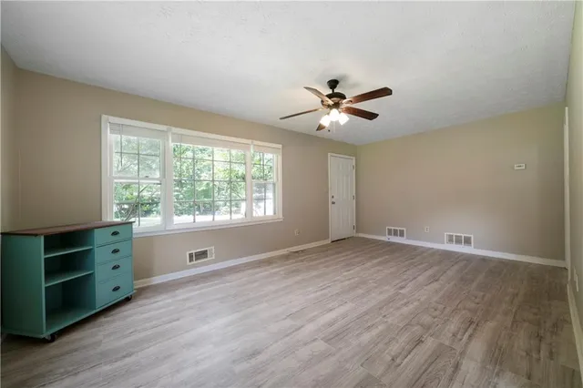 a view of an empty room with a window and wooden floor