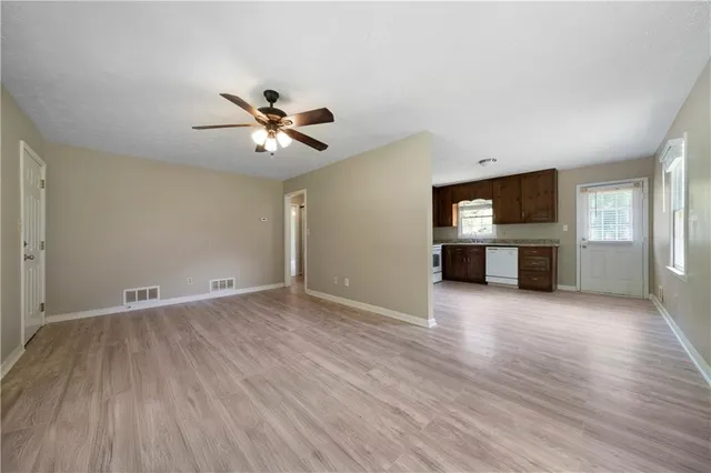 an empty room with wooden floor a fireplace and windows