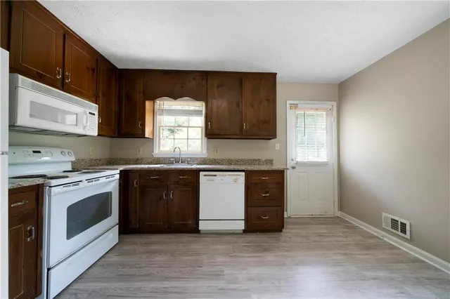 a kitchen with stainless steel appliances granite countertop a stove a sink and a microwave
