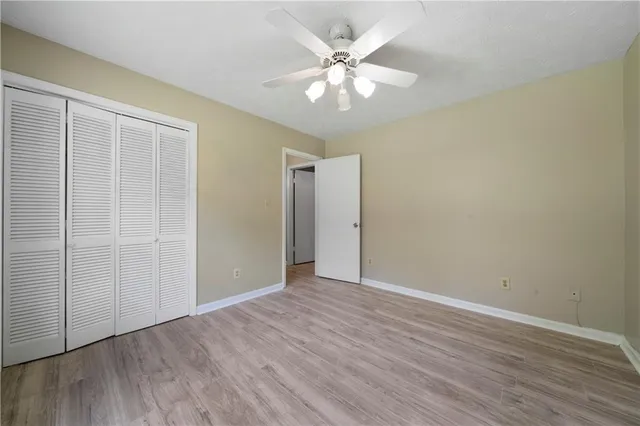 an empty room with wooden floor and fan
