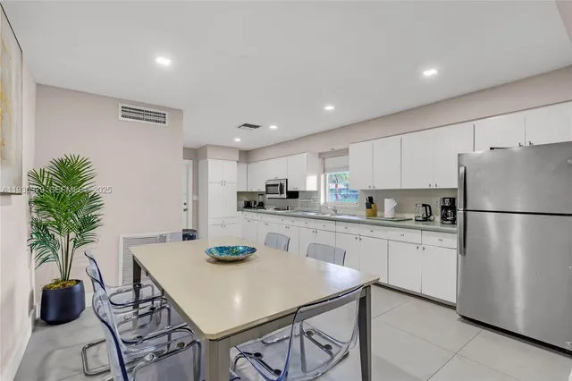a large white kitchen with lots of counter top space and furniture