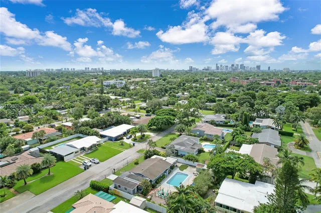 an aerial view of residential houses with outdoor space and trees