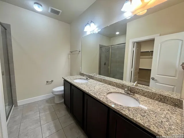 a bathroom with a granite countertop sink a toilet and a large mirror