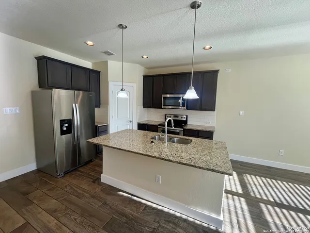a kitchen with stainless steel appliances granite countertop a sink refrigerator and microwave