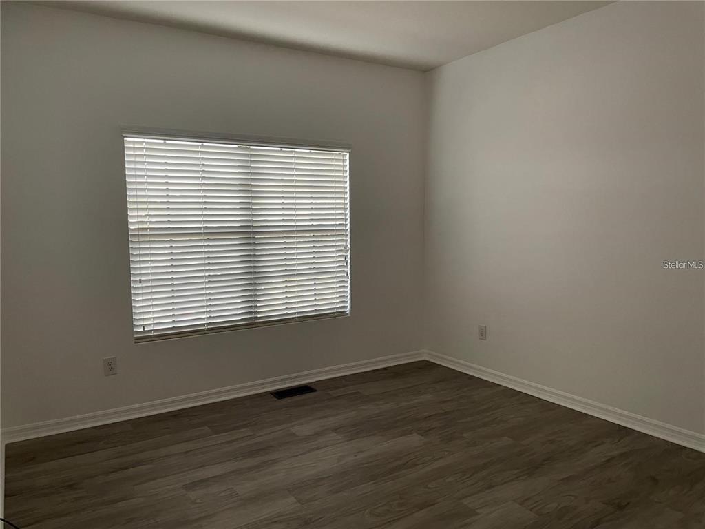 3408 Seneca Club Loop, Unit A Orlando, FL 32808 - Photo 13 of 36 an empty room with wooden floor and a window