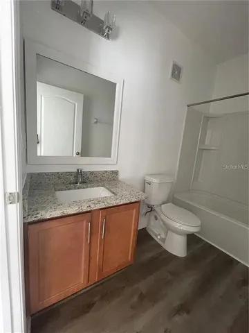 a bathroom with a granite countertop toilet sink and mirror