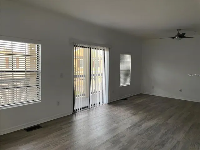 an empty room with wooden floor and windows
