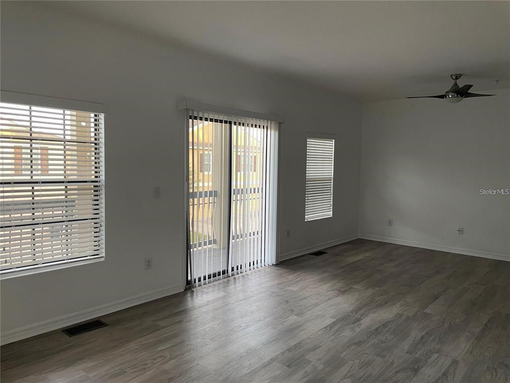 3408 Seneca Club Loop, Unit A Orlando, FL 32808 - Photo 7 of 36 an empty room with wooden floor and windows