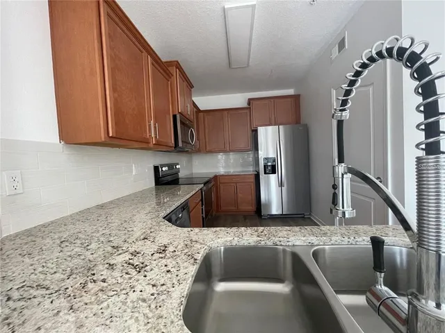 a kitchen with stainless steel appliances granite countertop a sink stove and refrigerator