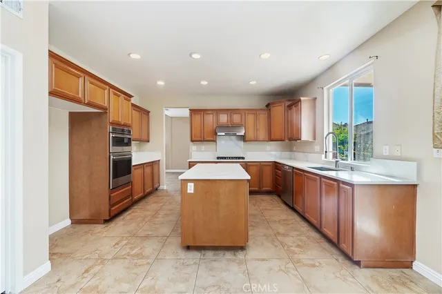 a large kitchen with stainless steel appliances kitchen island granite countertop a large counter top and a stove top oven