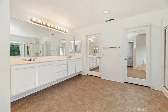 a spacious bathroom with a double vanity sink a mirror and a bathtub
