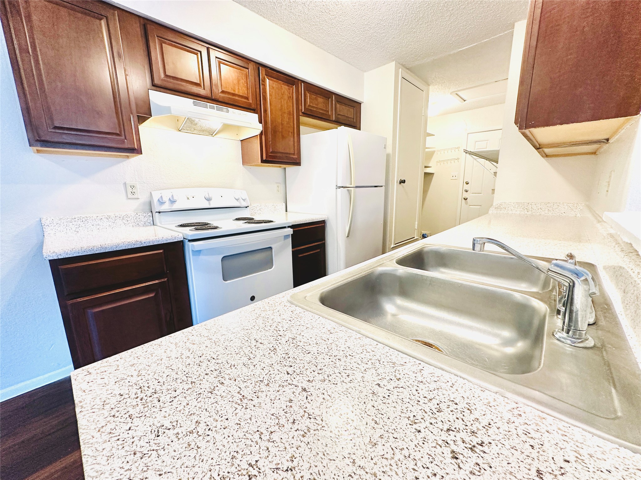 12505 Turtle Rock Road, Unit A Austin, TX 78729 - Photo 7 of 38 A functional kitchen features rich wood cabinetry, a double basin sink, and ample counter space.